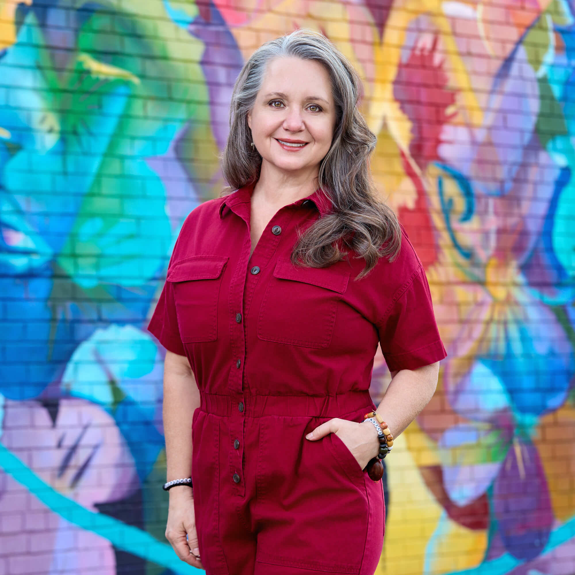 Michelle Fox CEO Portrait – Charlotte Branding Photography Alt Text Outdoor environmental portrait of Michelle Fox, CEO of Fenix Fotography, wearing a red jumpsuit against a colorful, painted mural backdrop in Charlotte, NC.