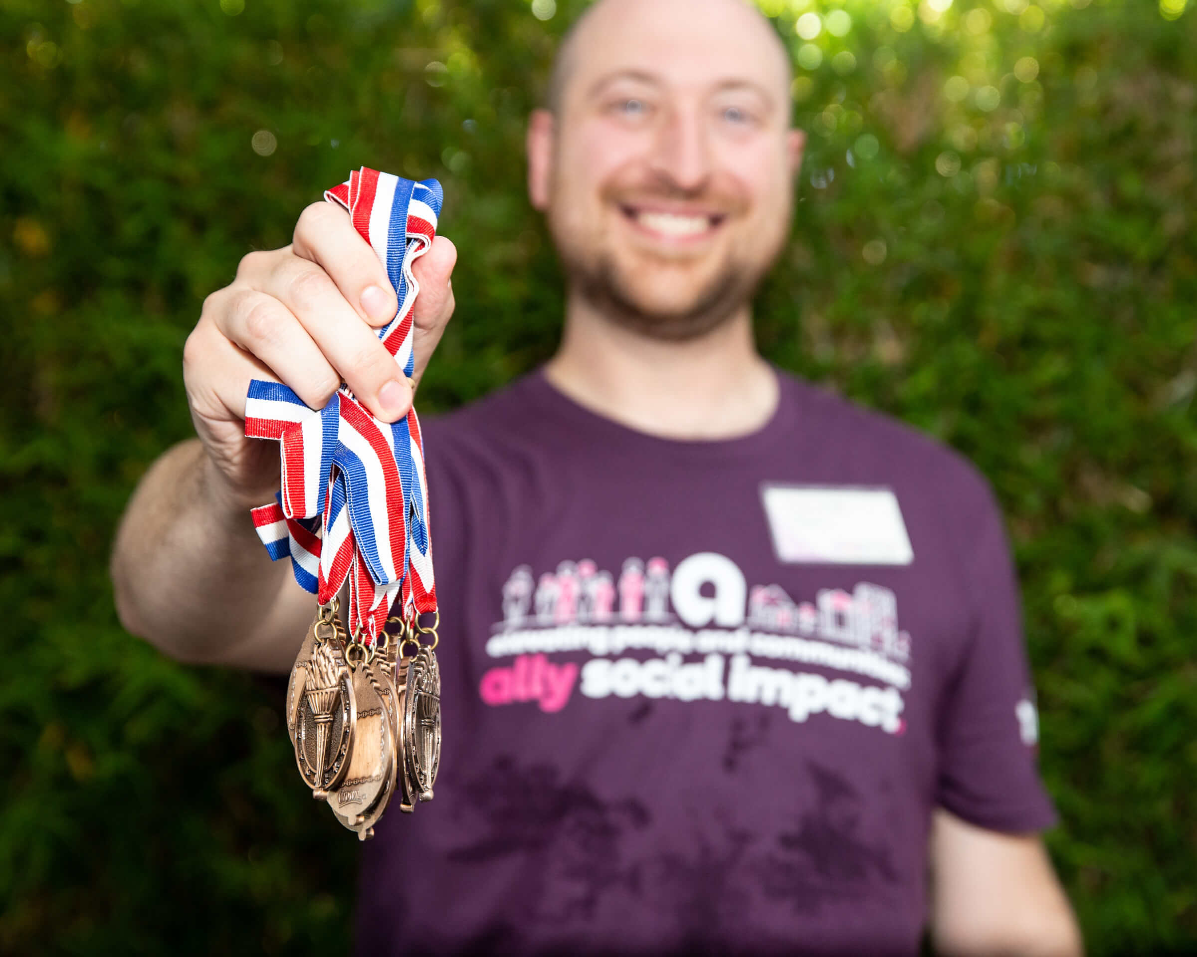 An Ally employee smiling outdoors while holding a medal at a team building event in Charleston, SC.