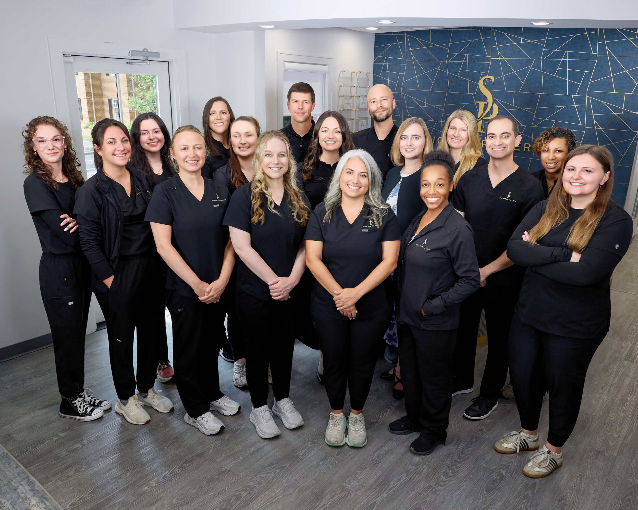 signature-periodontics-dental-team-group-photo Signature Periodontics team group photo showing staff and hygienists smiling together inside their office.