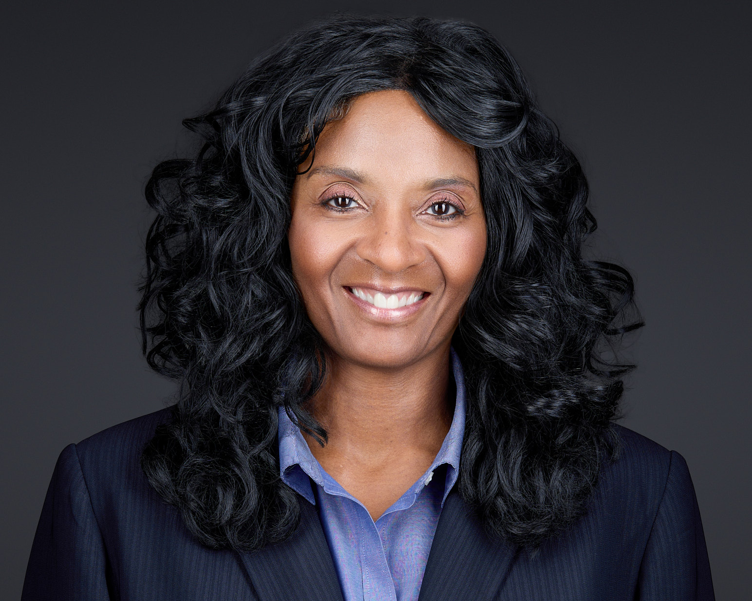 Corporate Studio Headshot – Charlotte Executive Photography Alt Text Studio headshot of a smiling Black female executive with curly hair against a dark background.