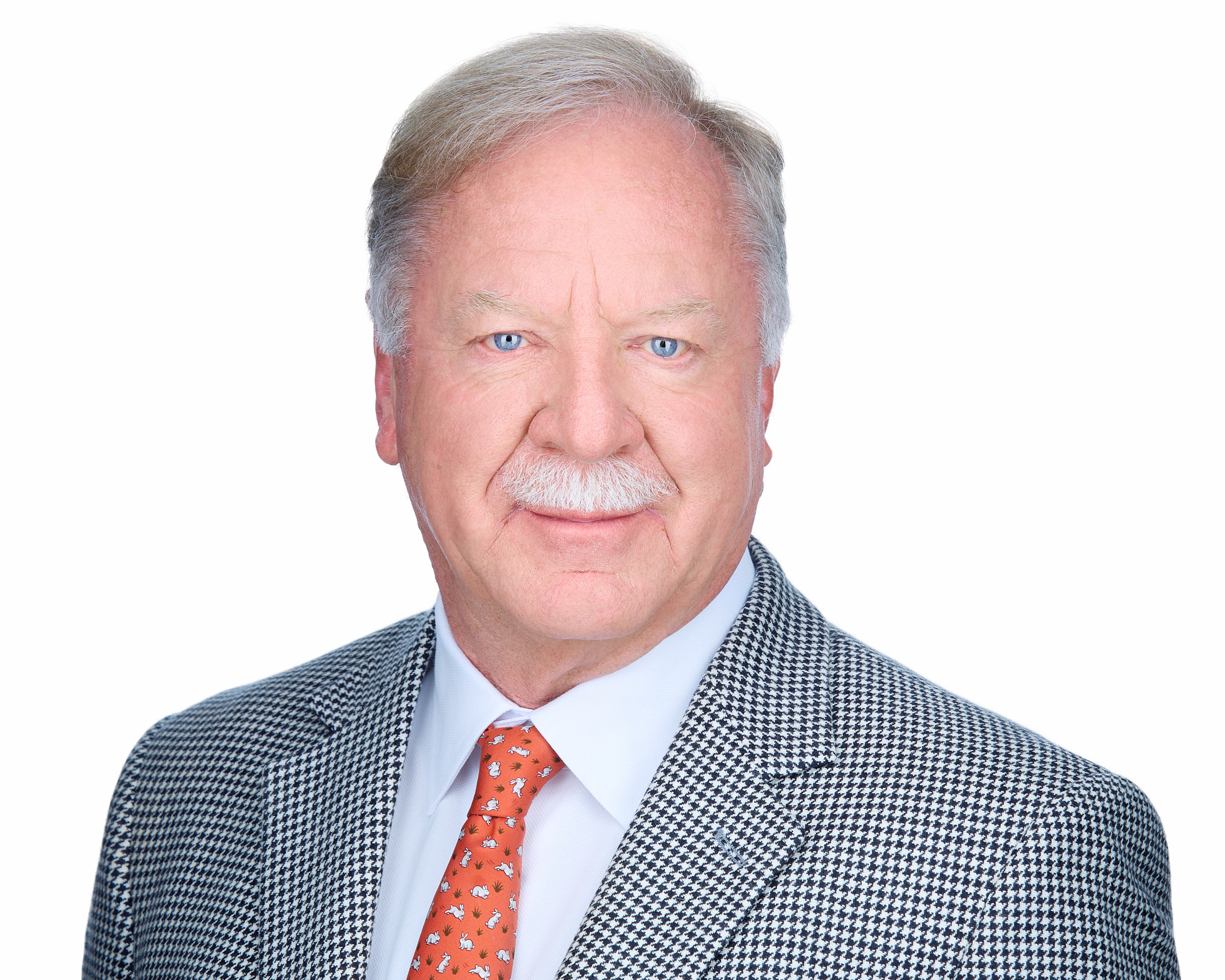 Corporate Studio Executive Headshot – Charlotte Photography Studio headshot of a smiling, older male corporate executive wearing glasses, a dark suit jacket, and a red tie against a plain white studio background.